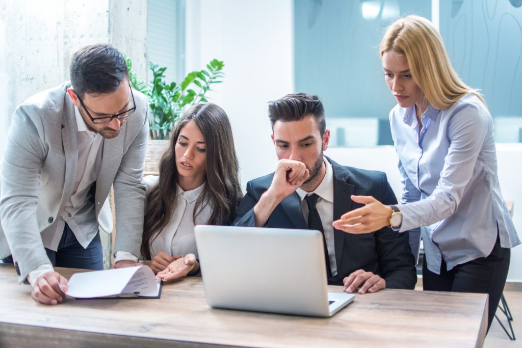 Group of worried and disappointed business people working in office and analyzing bad results from paperwork and laptop during office meeting