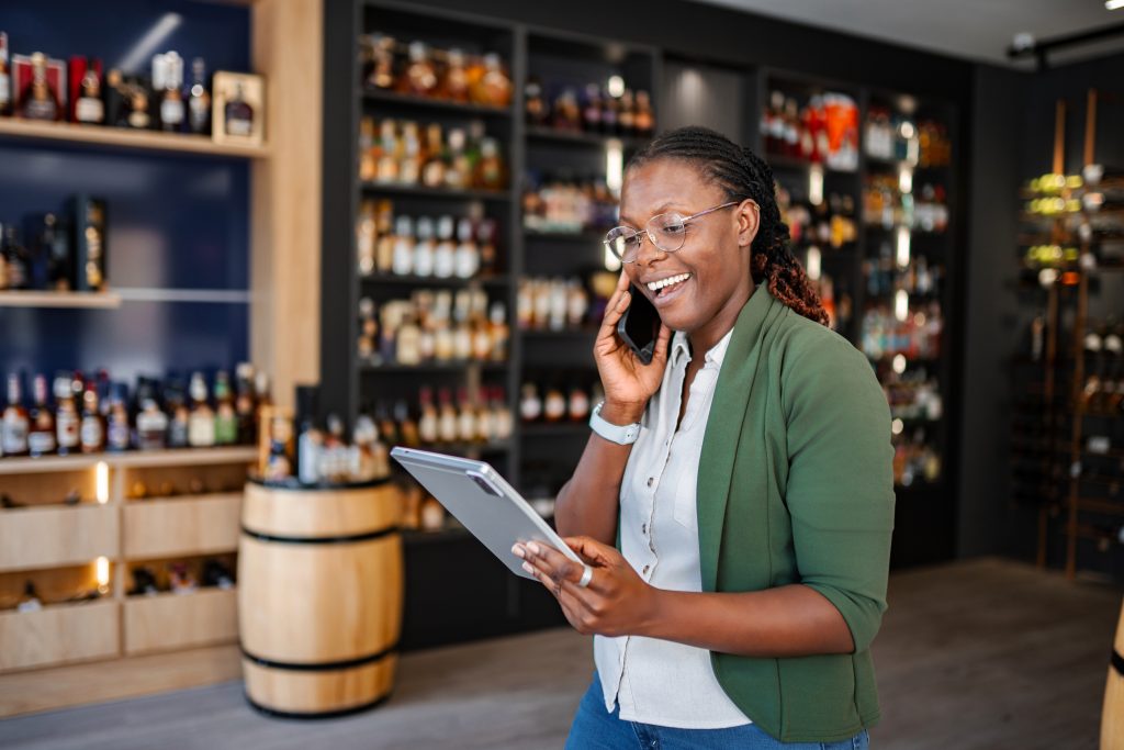 Smiling woman talking on phone and using tablet in a retail store